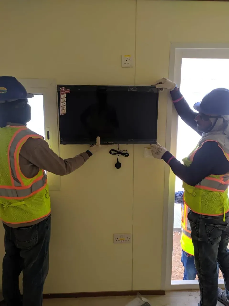 Jubail workforce-accommodation reference depicting smart TV installation inside labour camp accommodation rooms for the Aramco JGC project